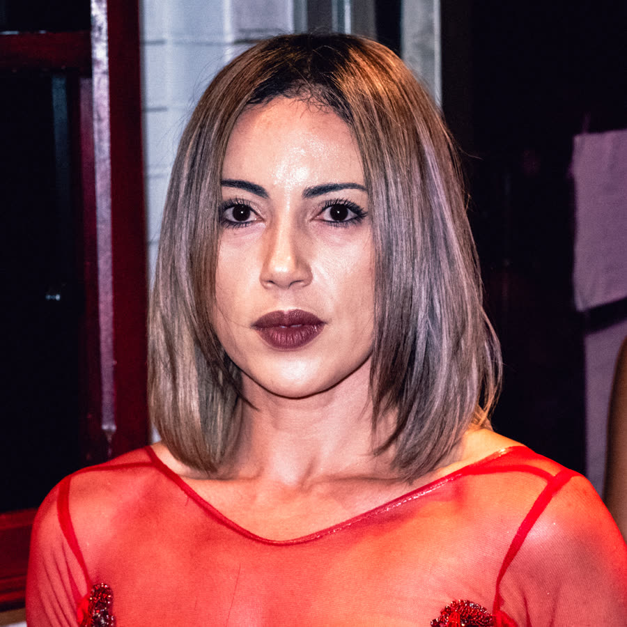 Model in a sheer red fashion look photographed with direct flash