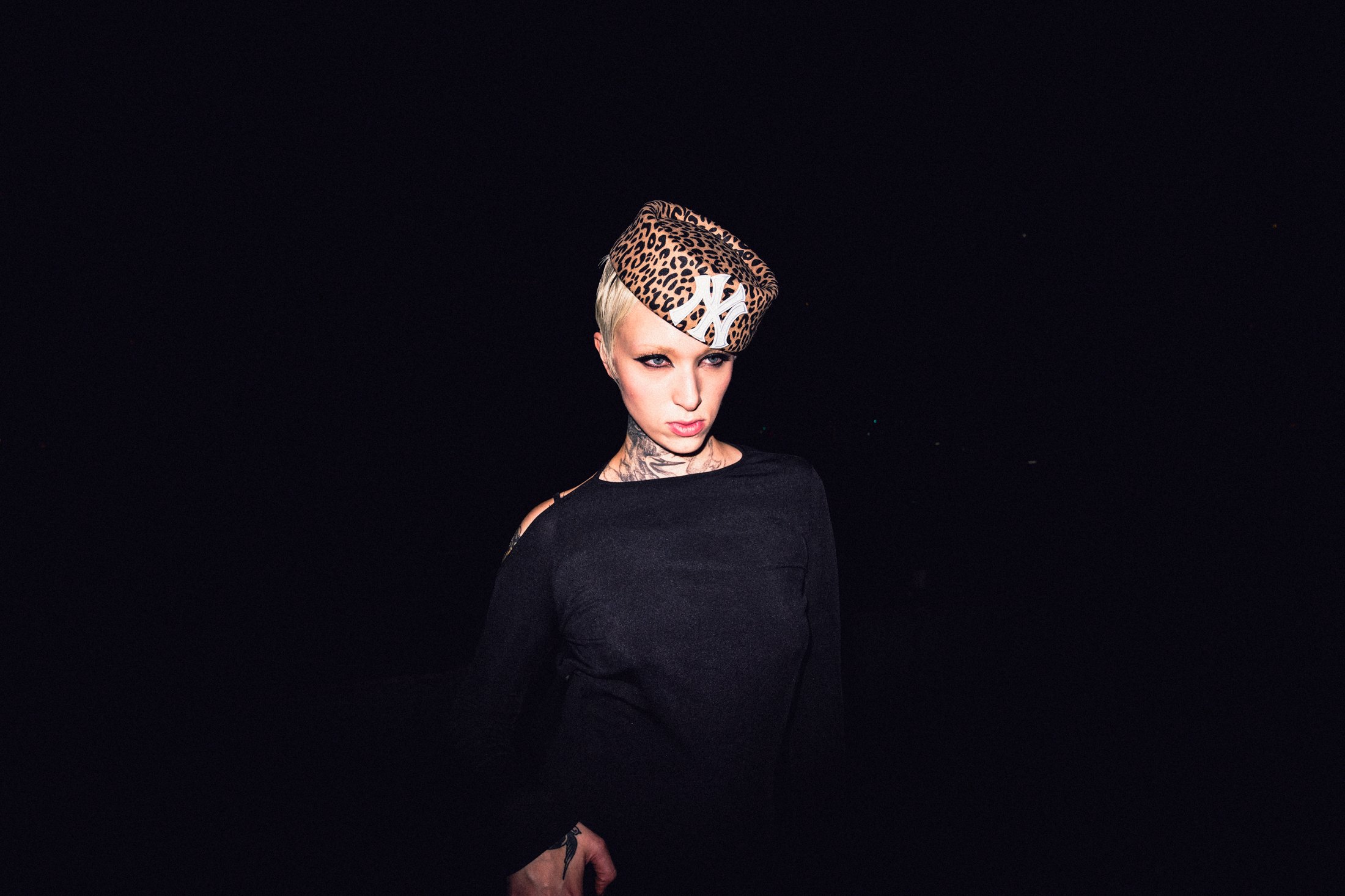 Model in a sculptural leopard headpiece isolated against black