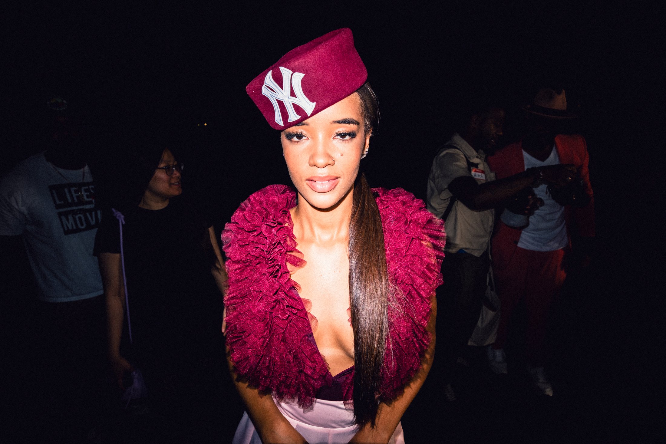 Model in a magenta feathered look and tilted New York cap