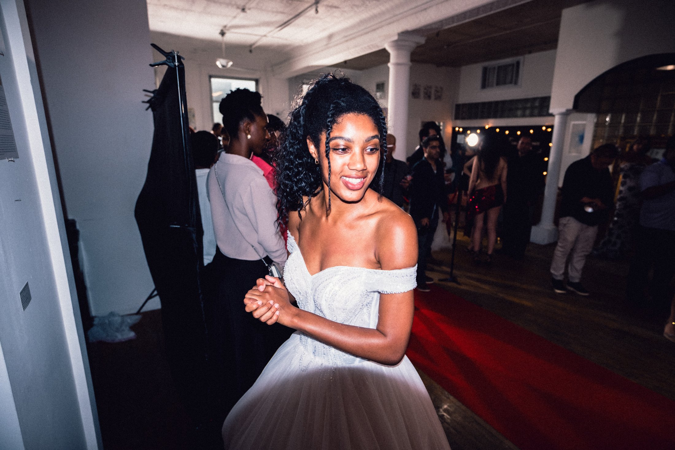 Model in a white gown smiling between runway moments